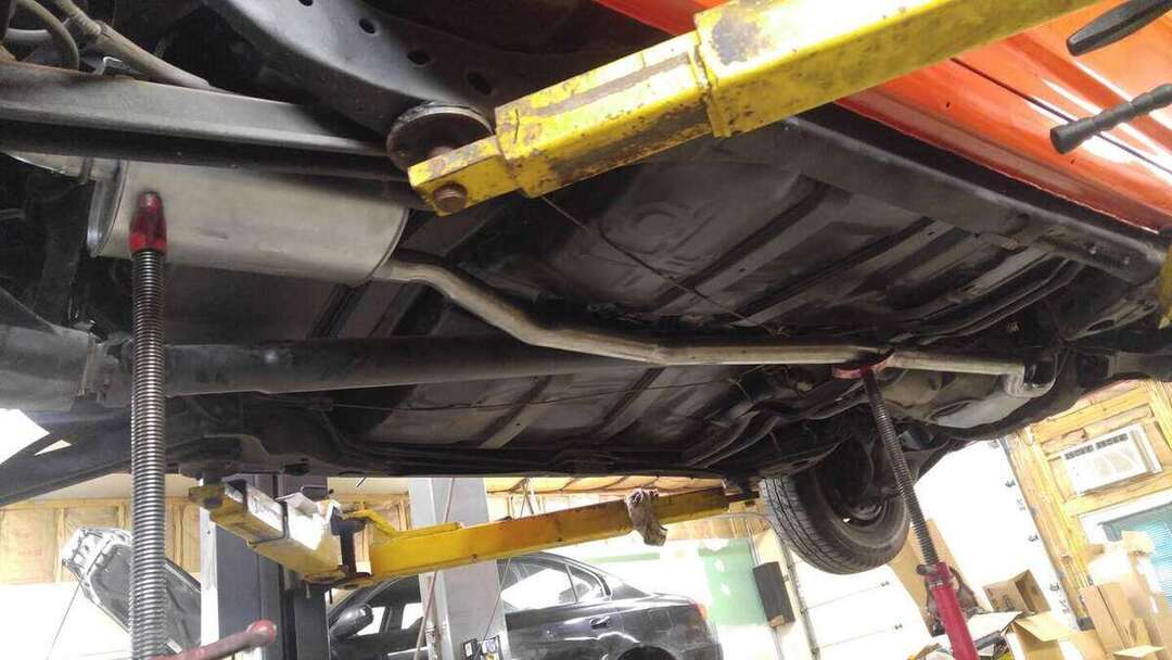 Custom exhaust routing checked beneath a red car