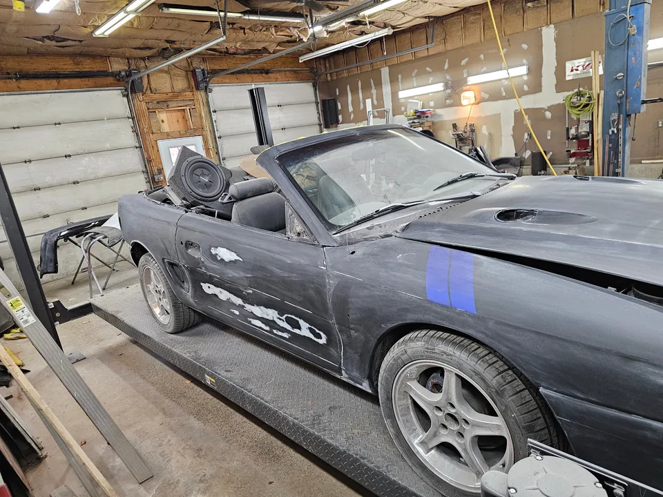 Passenger-side panels of the 1997 Ford Mustang GT convertible during sanding and surface preparation