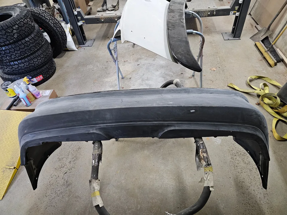Removed Mustang bumper cover on a stand with its surface sanded for paint preparation