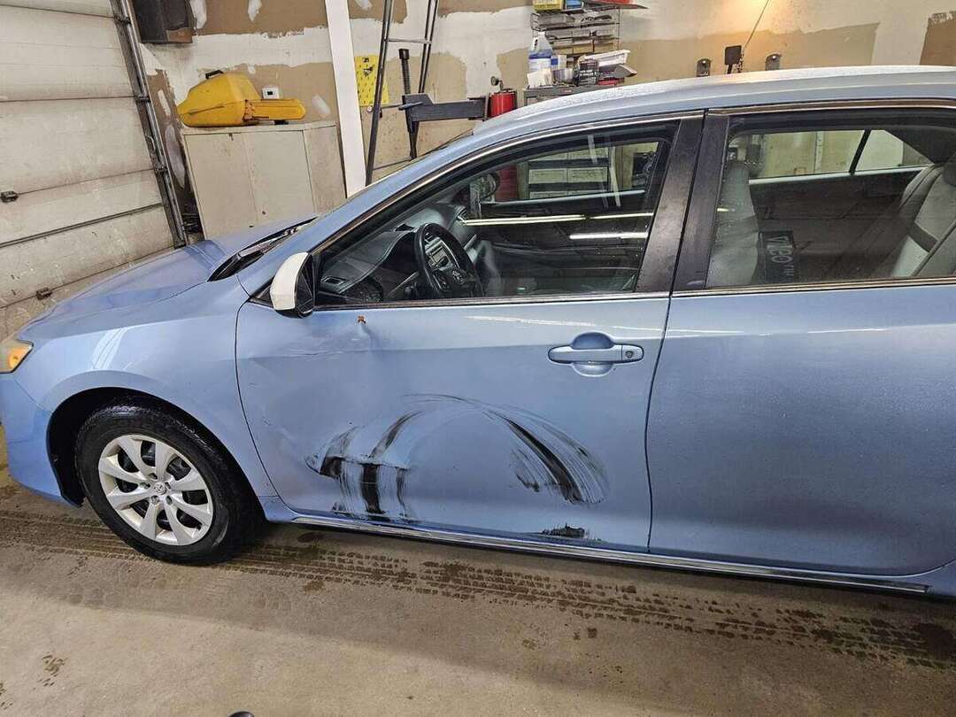Collision damage across the driver-side doors of a blue Toyota Camry