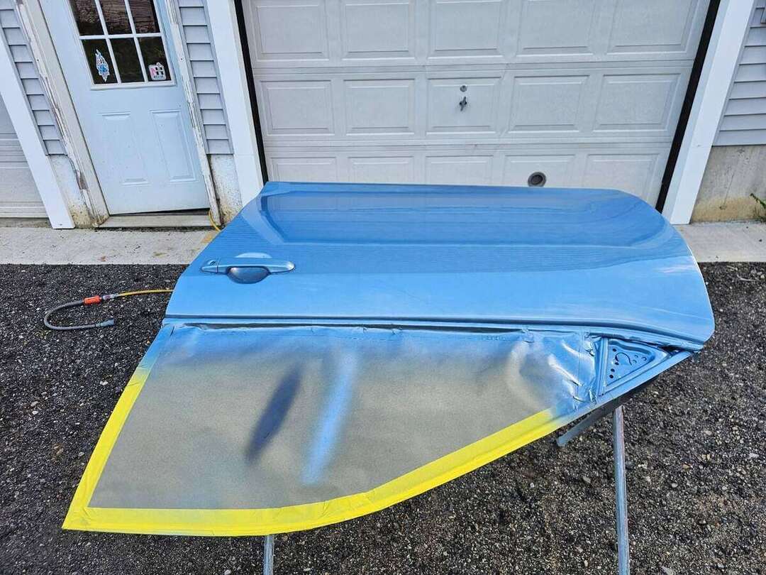 Blue basecoat being applied to a replacement Toyota Camry door
