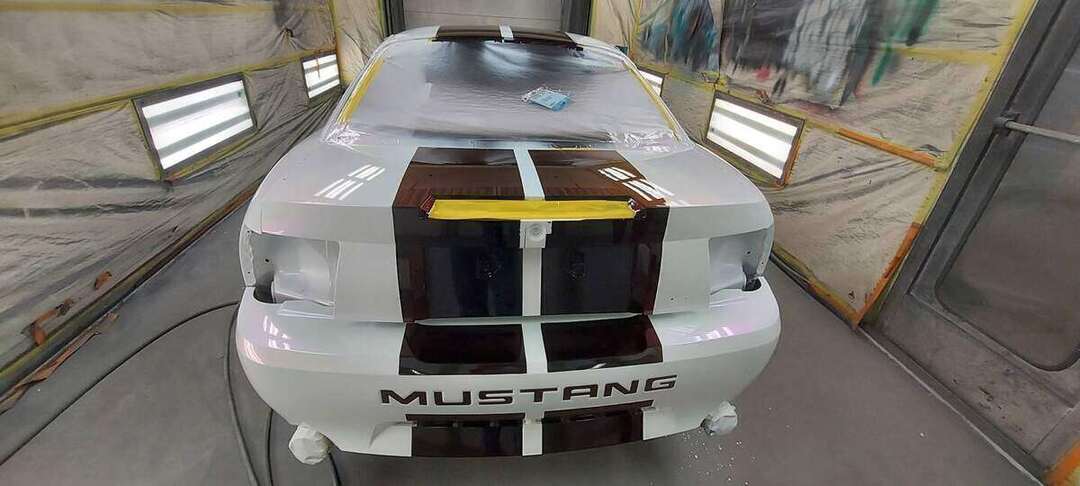 Burgundy stripes across the rear deck and bumper of a white Mustang