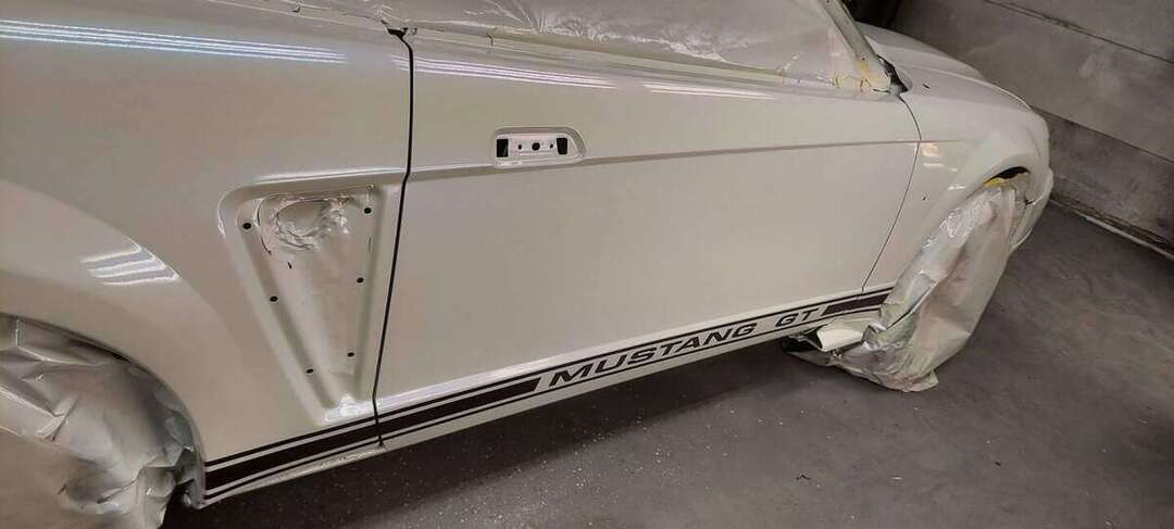 Passenger side of a white Mustang GT during final paint preparation