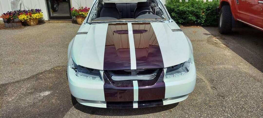 Completed white Mustang GT with burgundy stripes outdoors